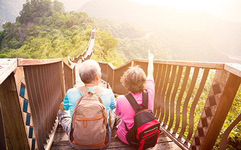 Photo of a senior couple sitting on stairs with a view of beautiful greenery. 